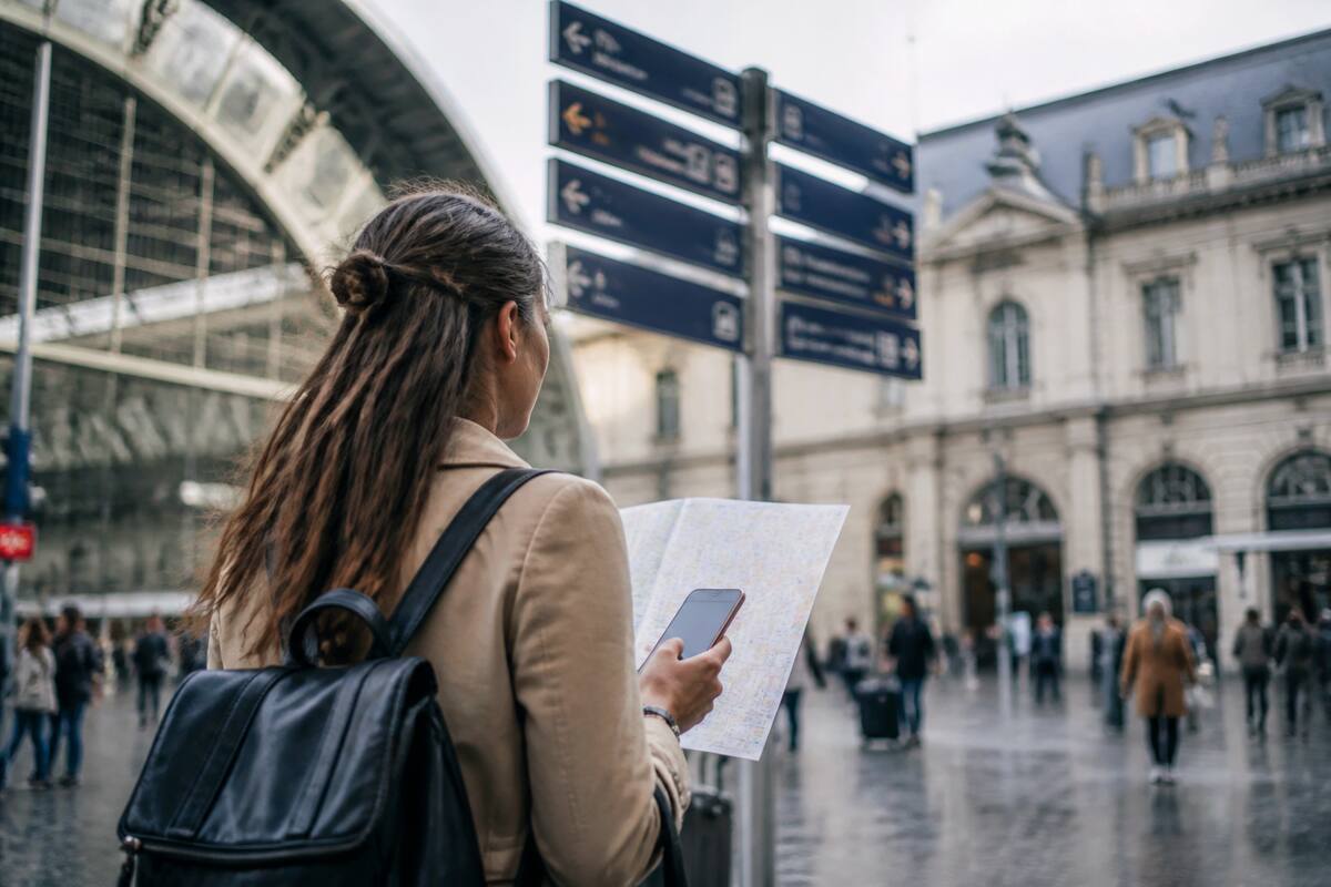 Reiziger met kaart en smartphone bij een treinstation in Europa