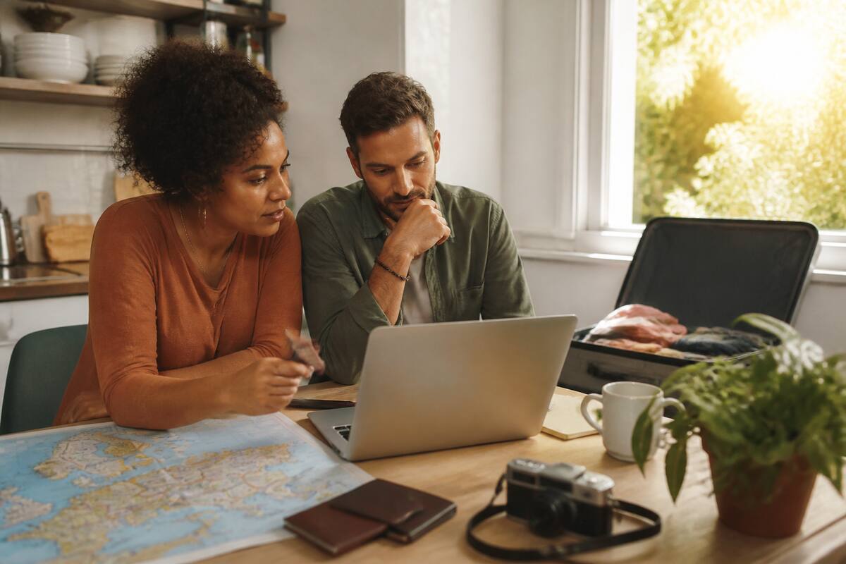 Reizen en vakanties vergelijken met een laptop en reisdocumenten aan tafel